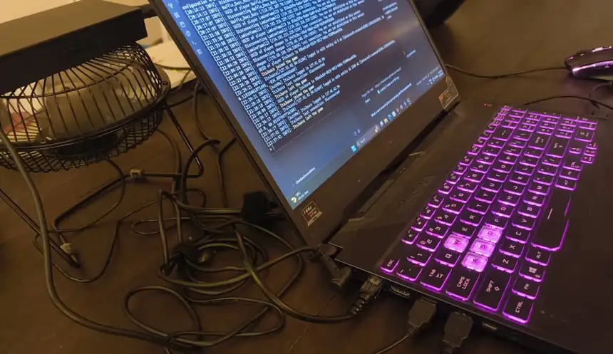 The server laptop on a desk, USB fan beside it, cables running to the wall.