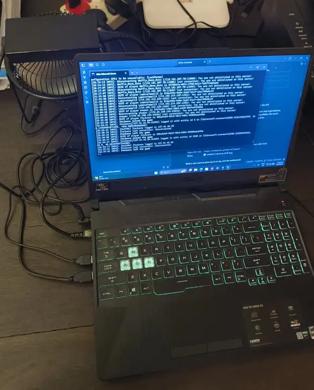 The same laptop from the front, router and plug behind it, server console on screen.